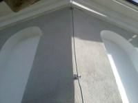 Прокладка токоотвода из оцинкованной стали по бетонной стене на углу дома с помощью универсальных держателей